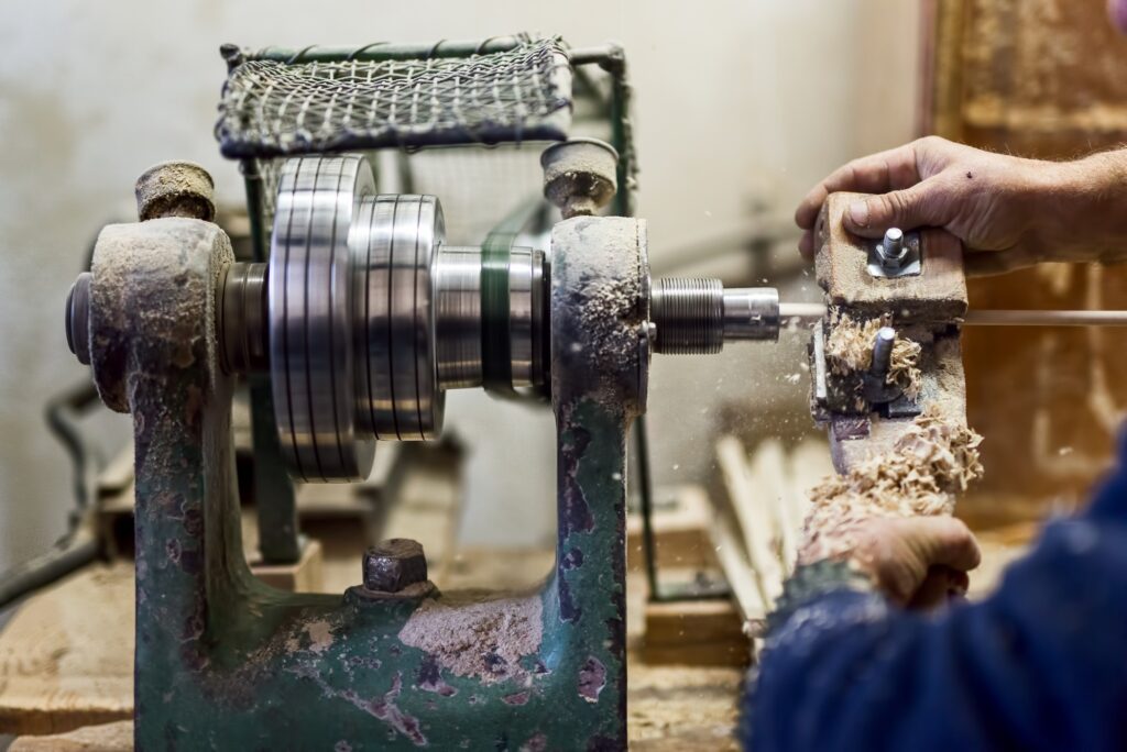 worker hands using woodturning lathe tool and other industry tools