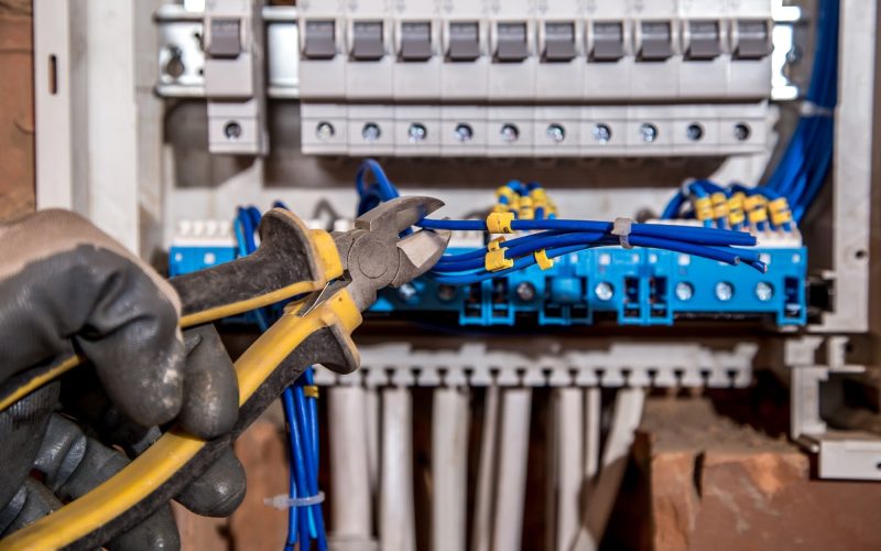 the Assembly of the electrical panel, electrician job, a robot with wires and circuit breakers